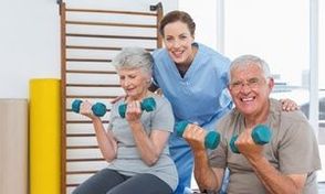 Female therapist assisting senior couple with dumbbells